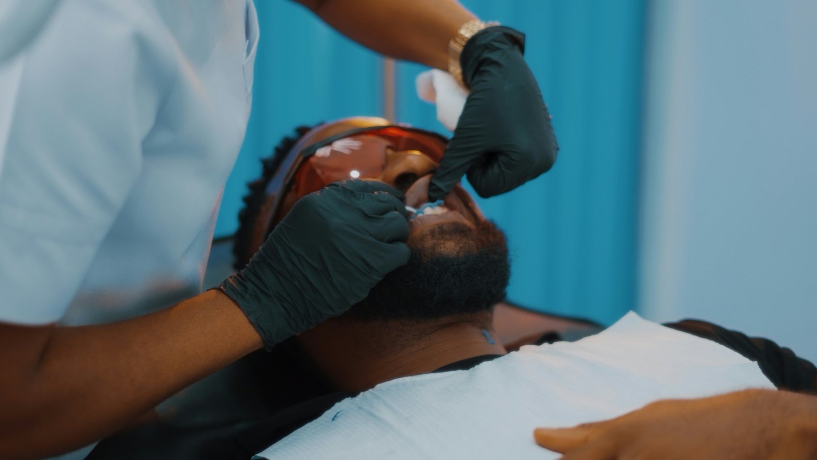 A dentist in gloves treating a patient reclined in the dental chair.